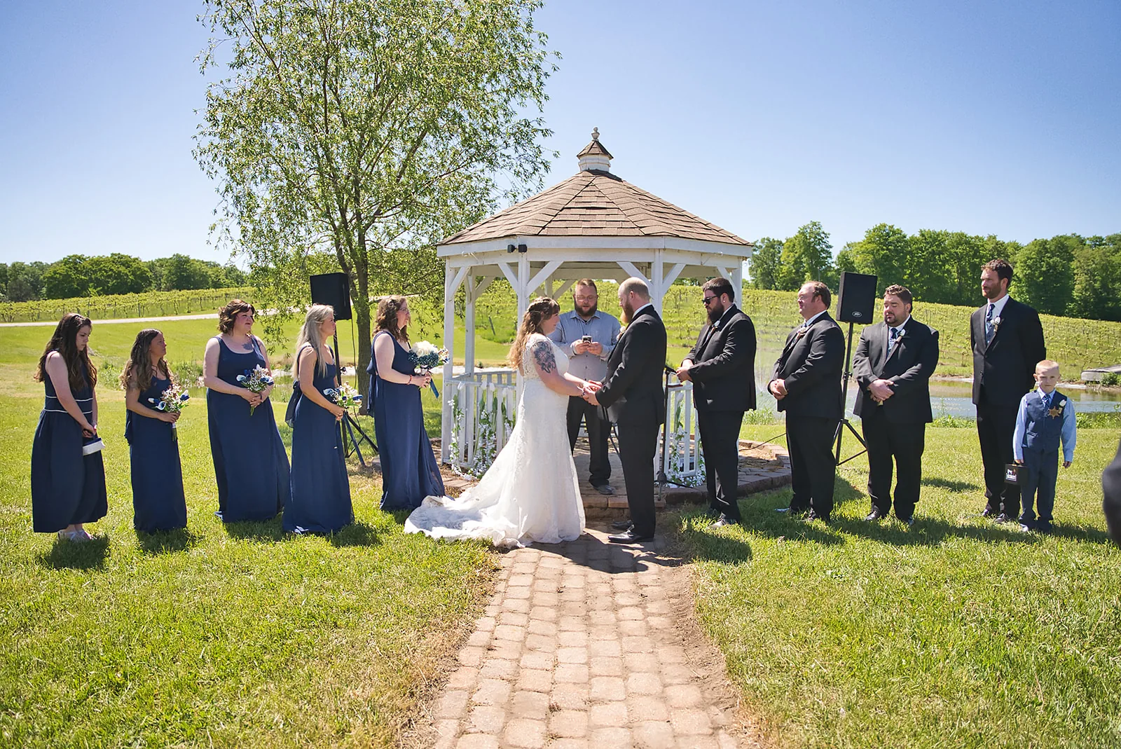 bride and groom with officiant walking down aisle, wine barrels