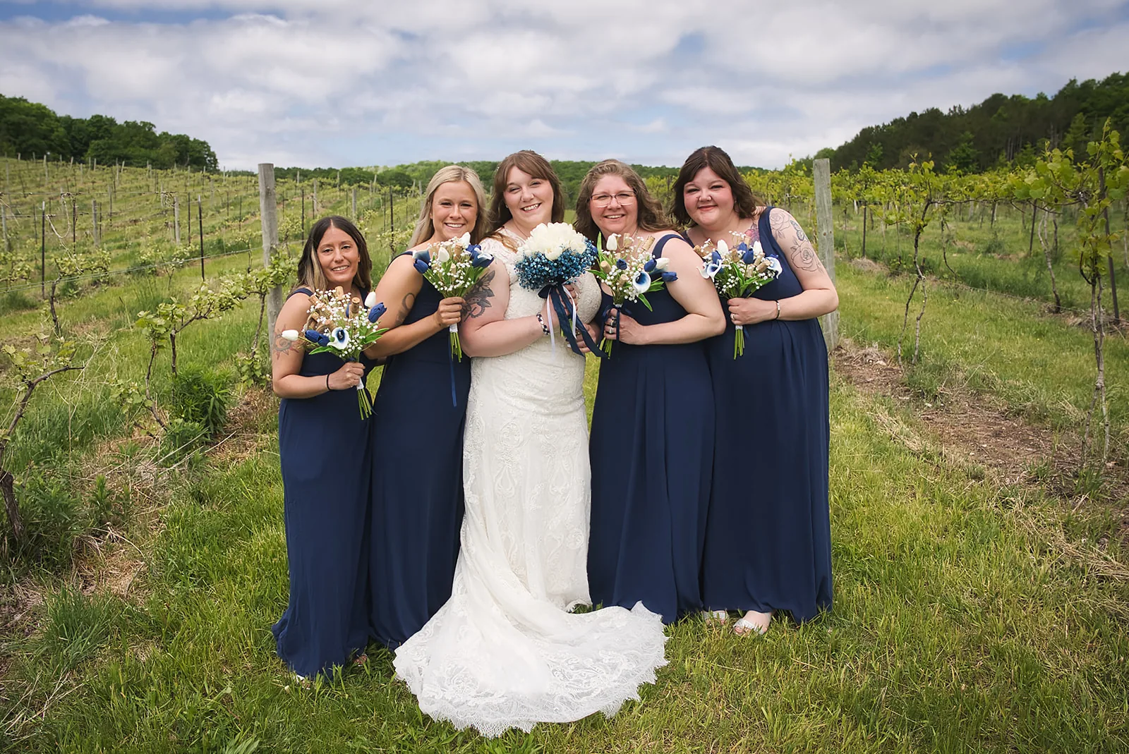 bridesmaids group portrait in navy dresses, vineyard backdrop