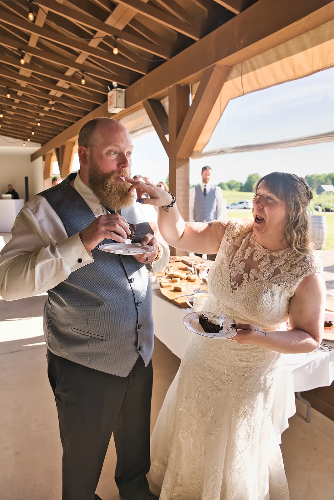 groom feeding bride cake at reception, candid