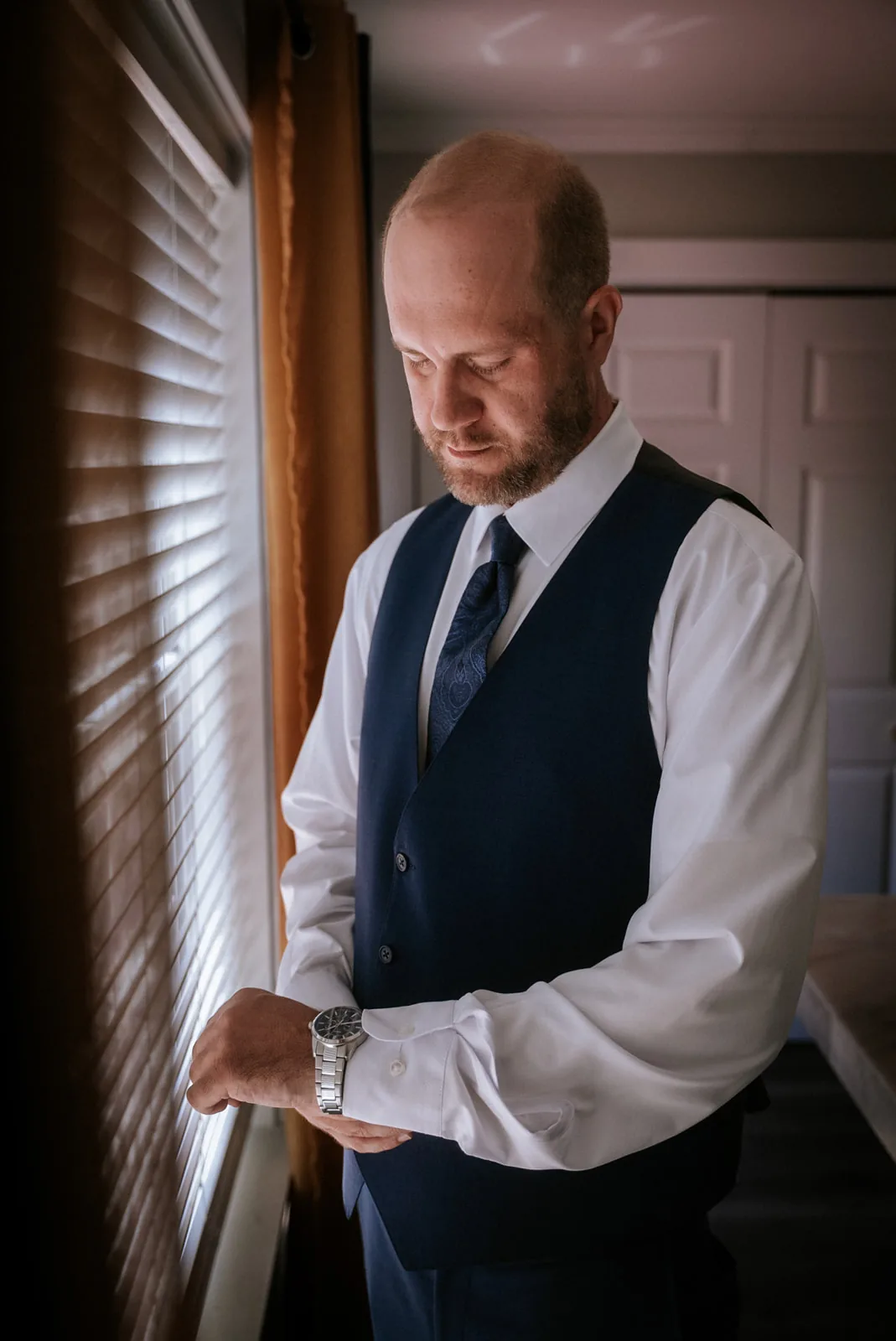 groom getting ready, looking out window, buttoning cuff