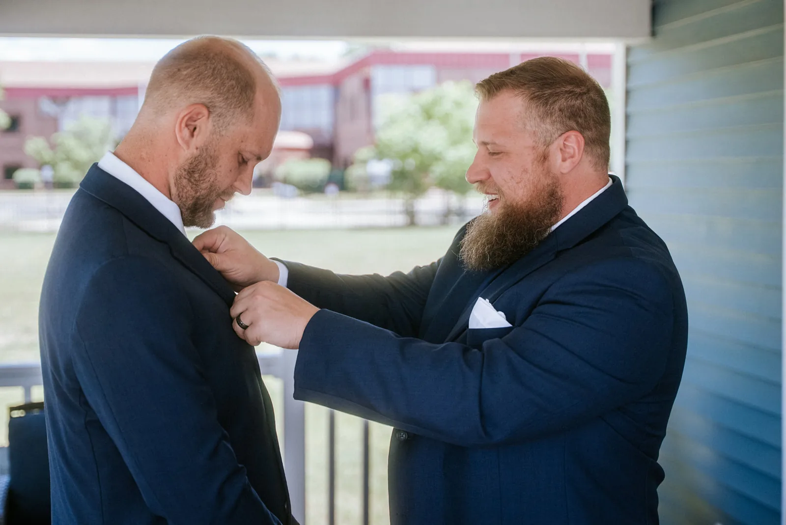 groomsman helping groom with boutonniere, getting ready porch