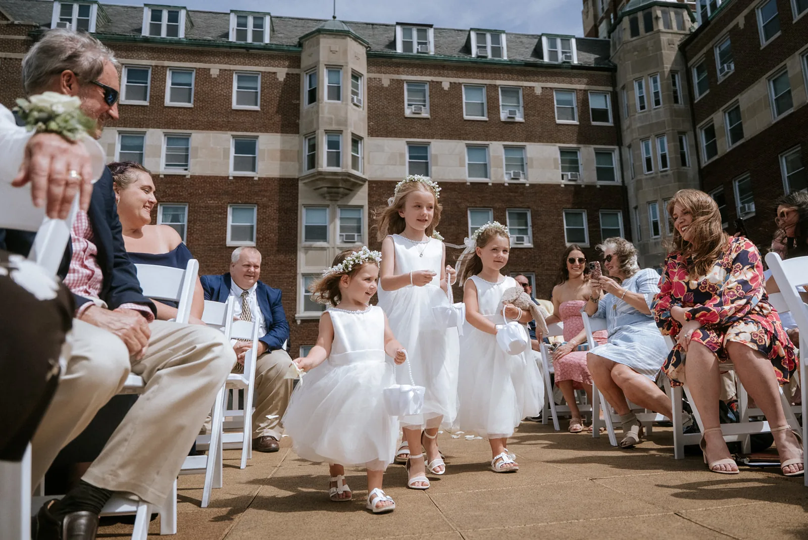 flower girls walking down rooftop aisle, guests seated