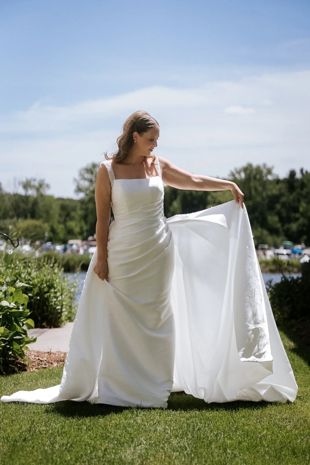 bride solo portrait outdoors holding dress train, lake view
