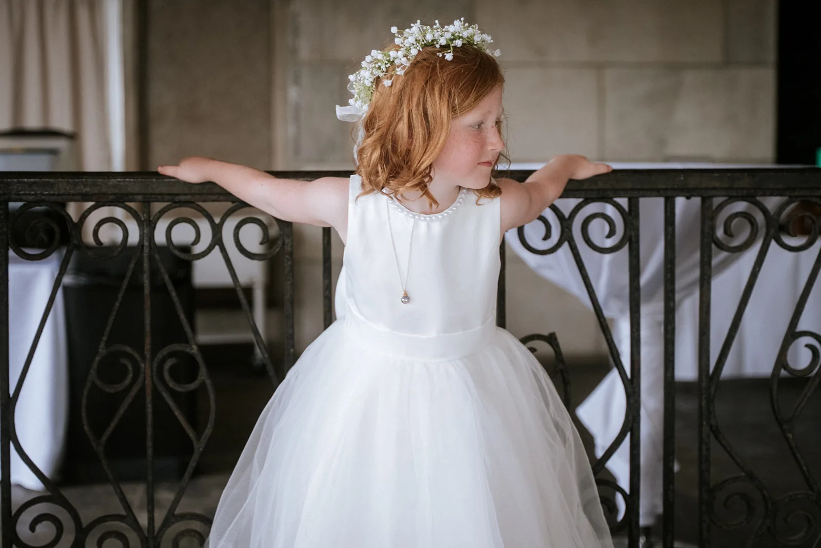 flower girl candid walking along railing, rooftop venue
