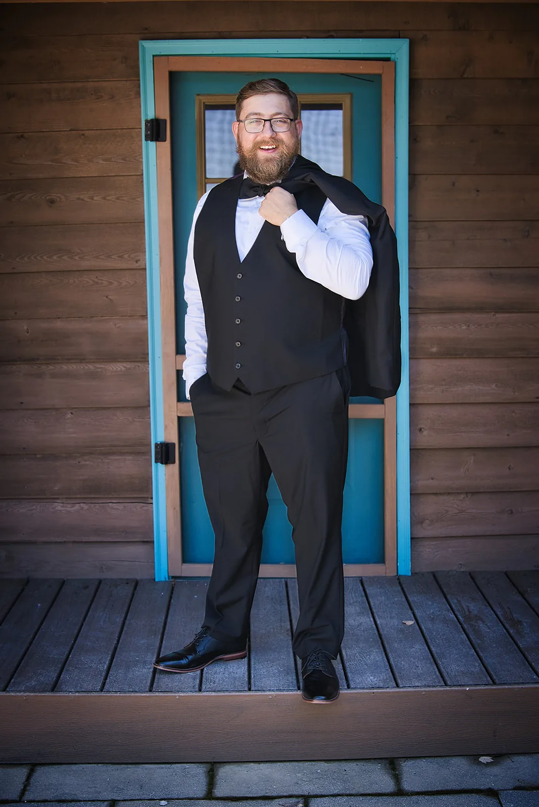 groom solo portrait seated by window, adjusting cufflink