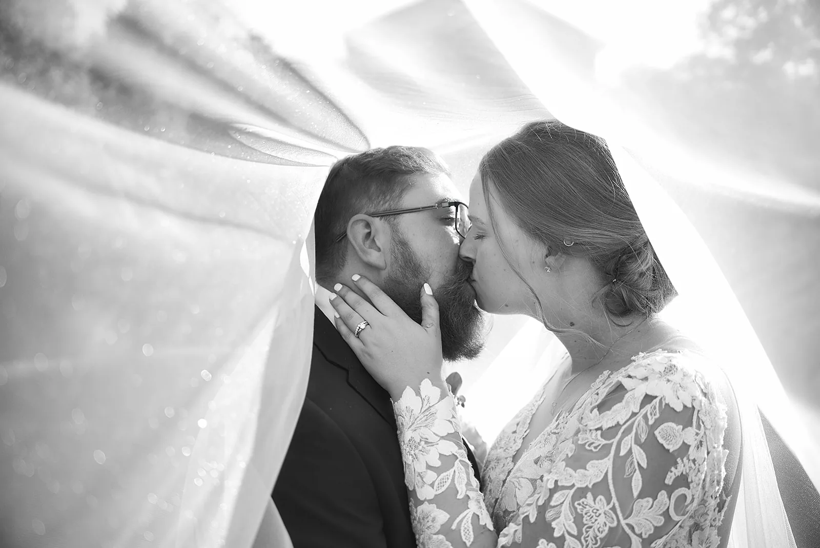 bw bride and groom kissing under windblown veil