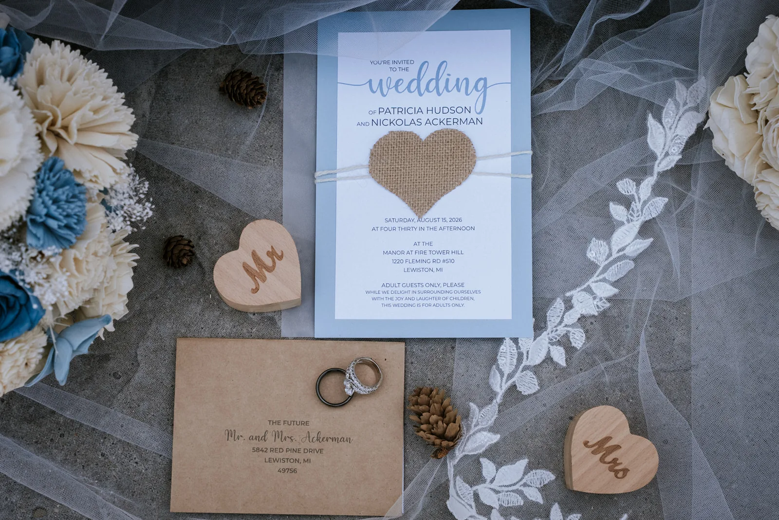 detail flatlay of invitation suite, rings, dried flowers and wood hearts
