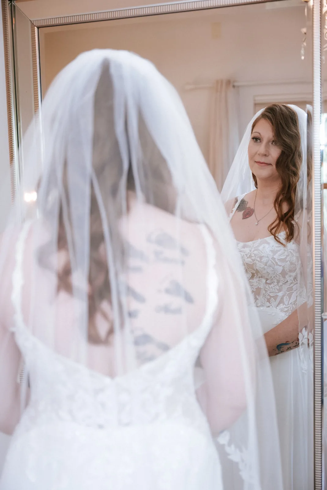 bride looking in mirror at reflection, veil and lace back detail