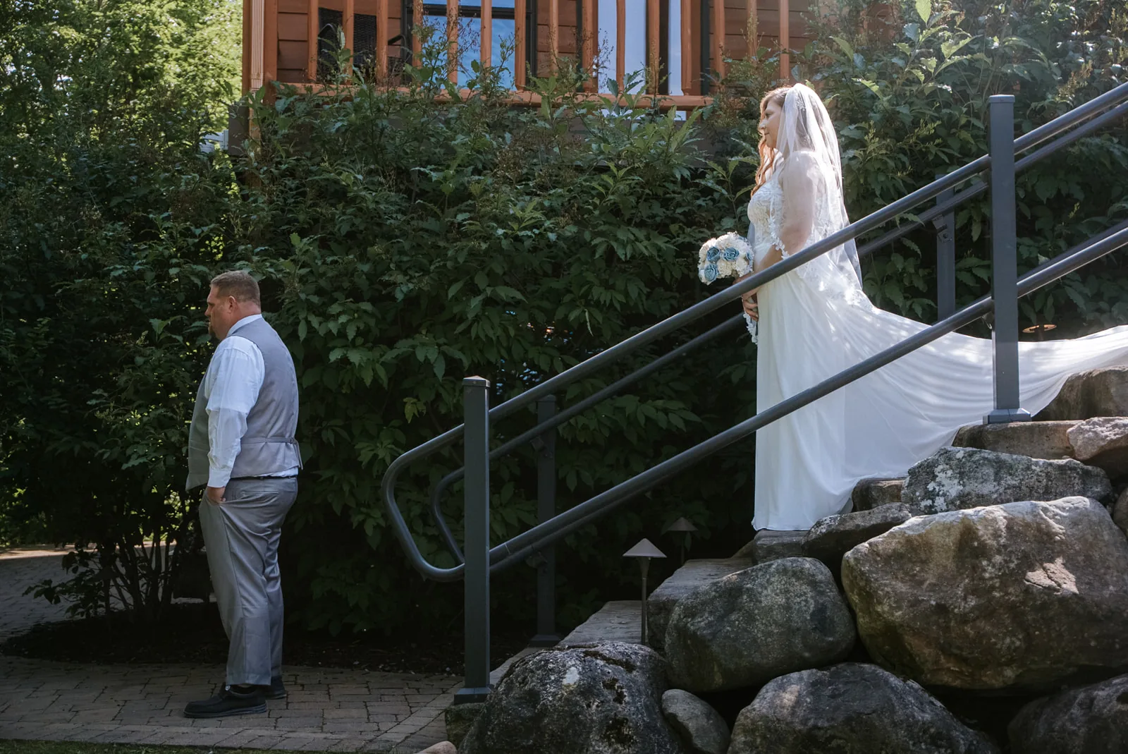 groom waiting at base of stone staircase for first look