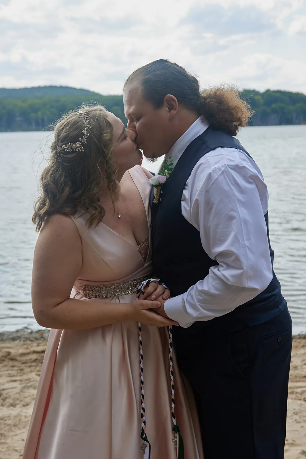 bride and groom kissing at lakeside ceremony altar