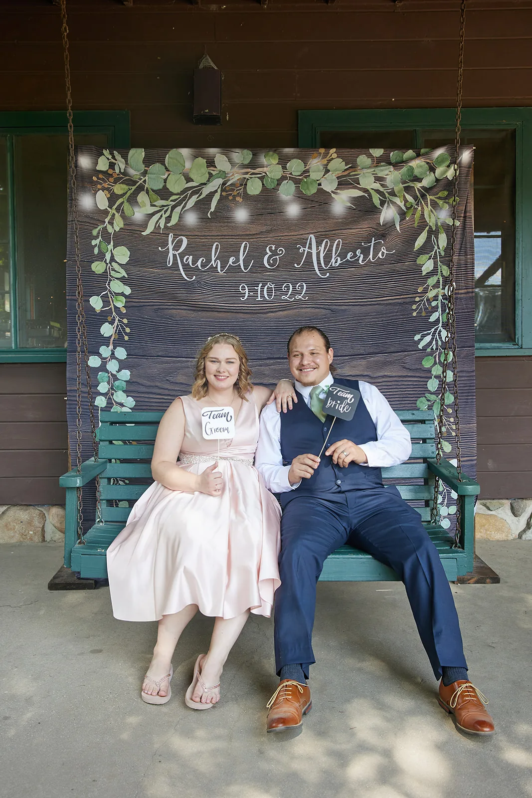 bride and groom seated on porch swing, custom "Rachel & Alberto" sign