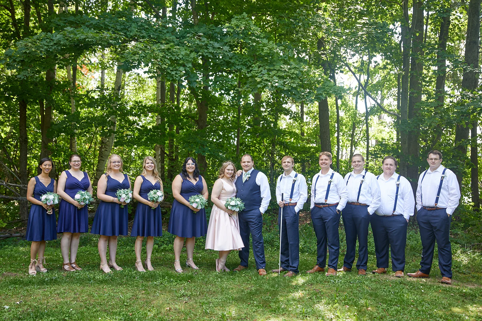 wide shot of full wedding party group portrait in forest clearing