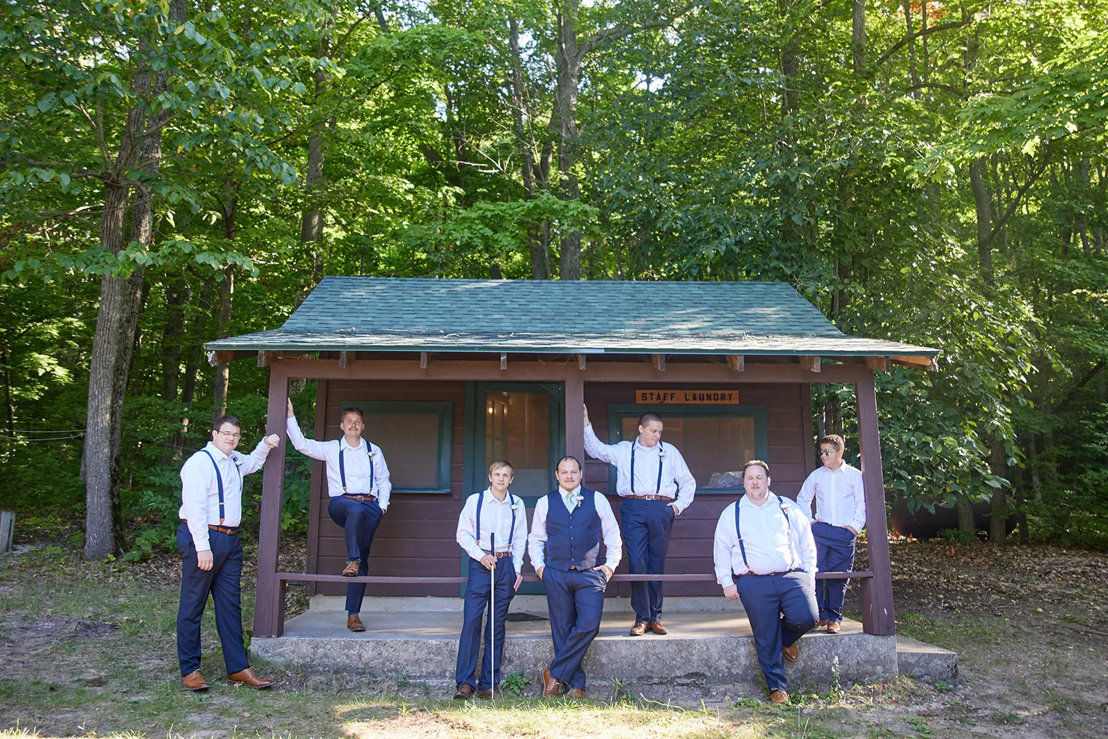 groomsmen group candid on cabin porch, wide shot forest