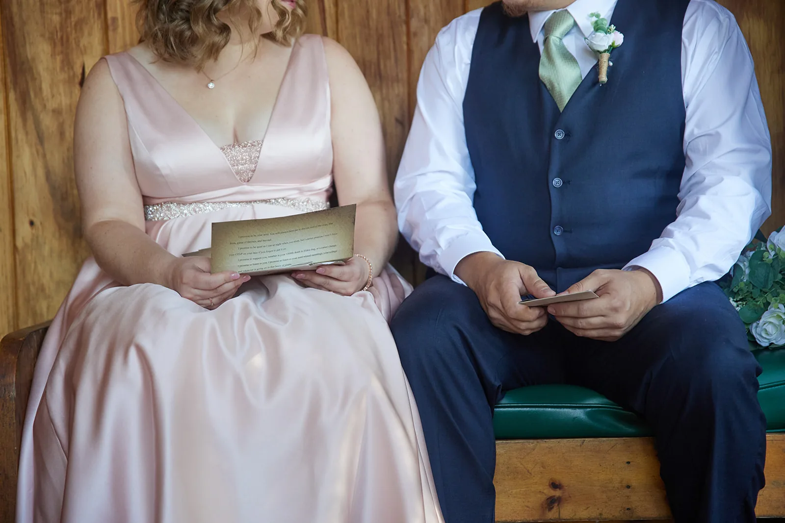 bride and groom seated together indoors, wood paneled wall, candid