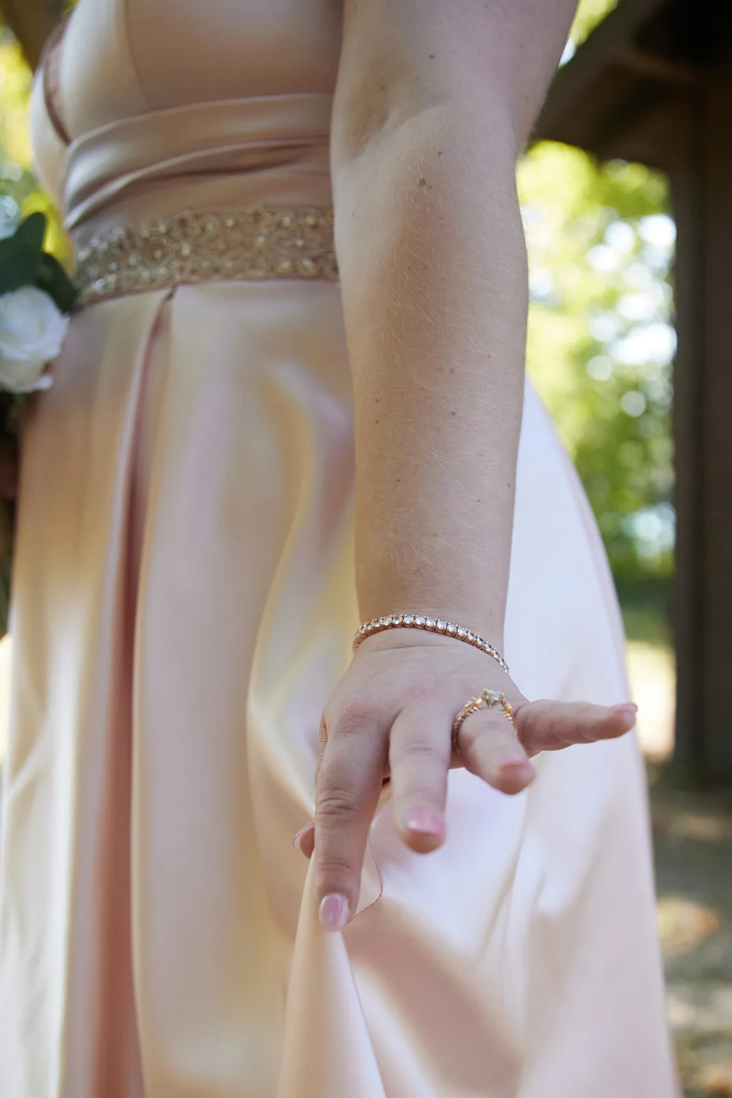 detail of brides hand and dress fabric, bracelet visible