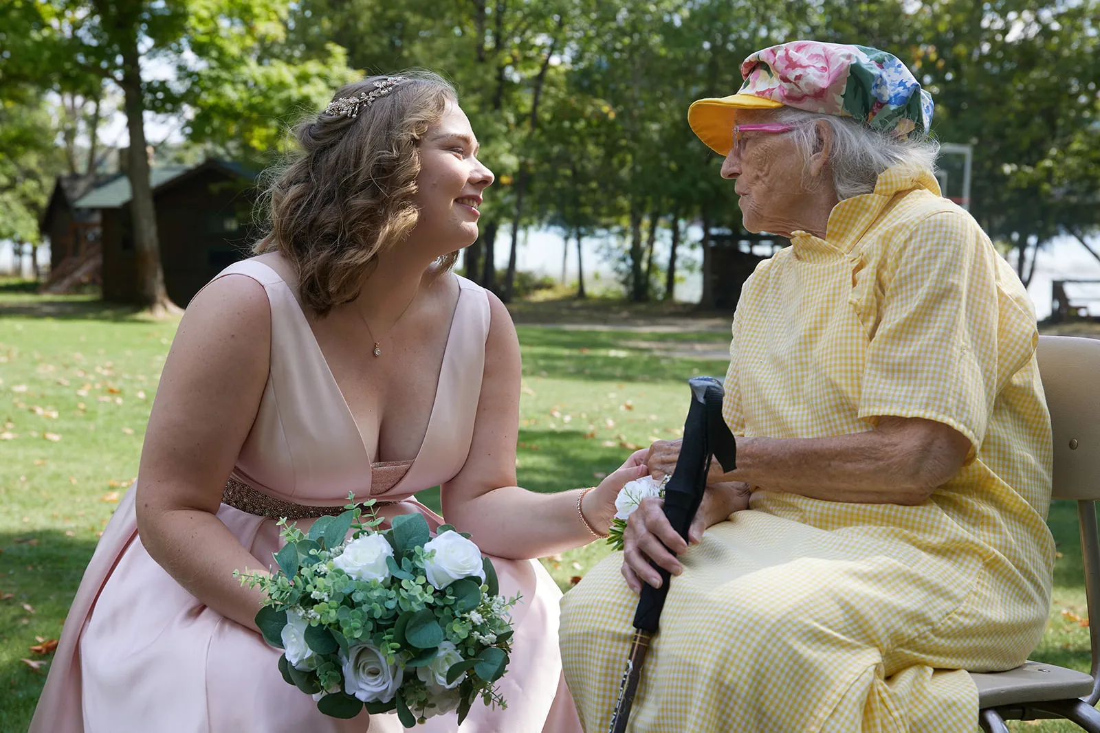 bridesmaid crouching to greet elderly guest, candid outdoors