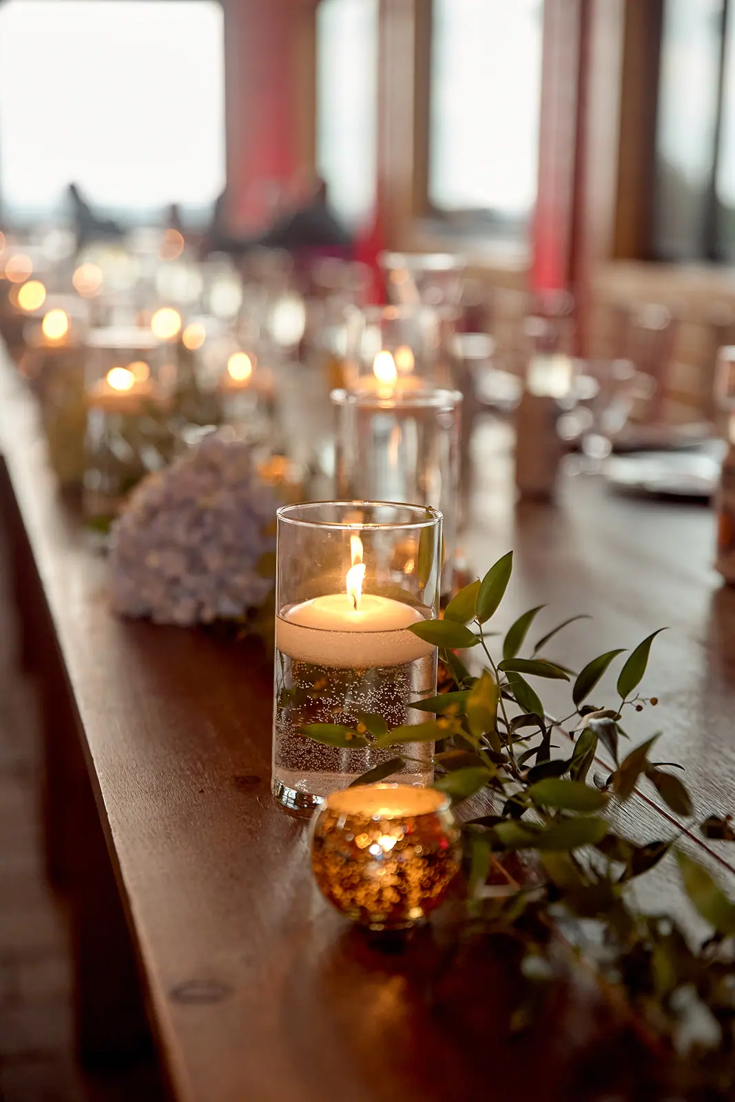 Candle greenery centrepieces long wooden table — Taylor & Mark's wedding at The Manor at Fire Tower Hill, Lewiston, MI