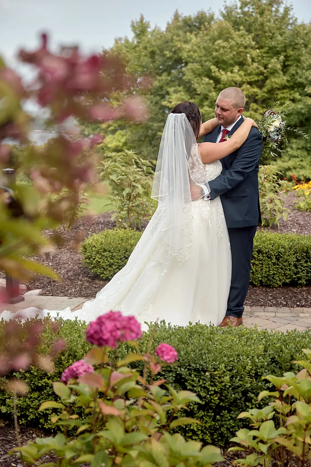 Couple embracing among pink flowers garden — Taylor & Mark's wedding at The Manor at Fire Tower Hill, Lewiston, MI