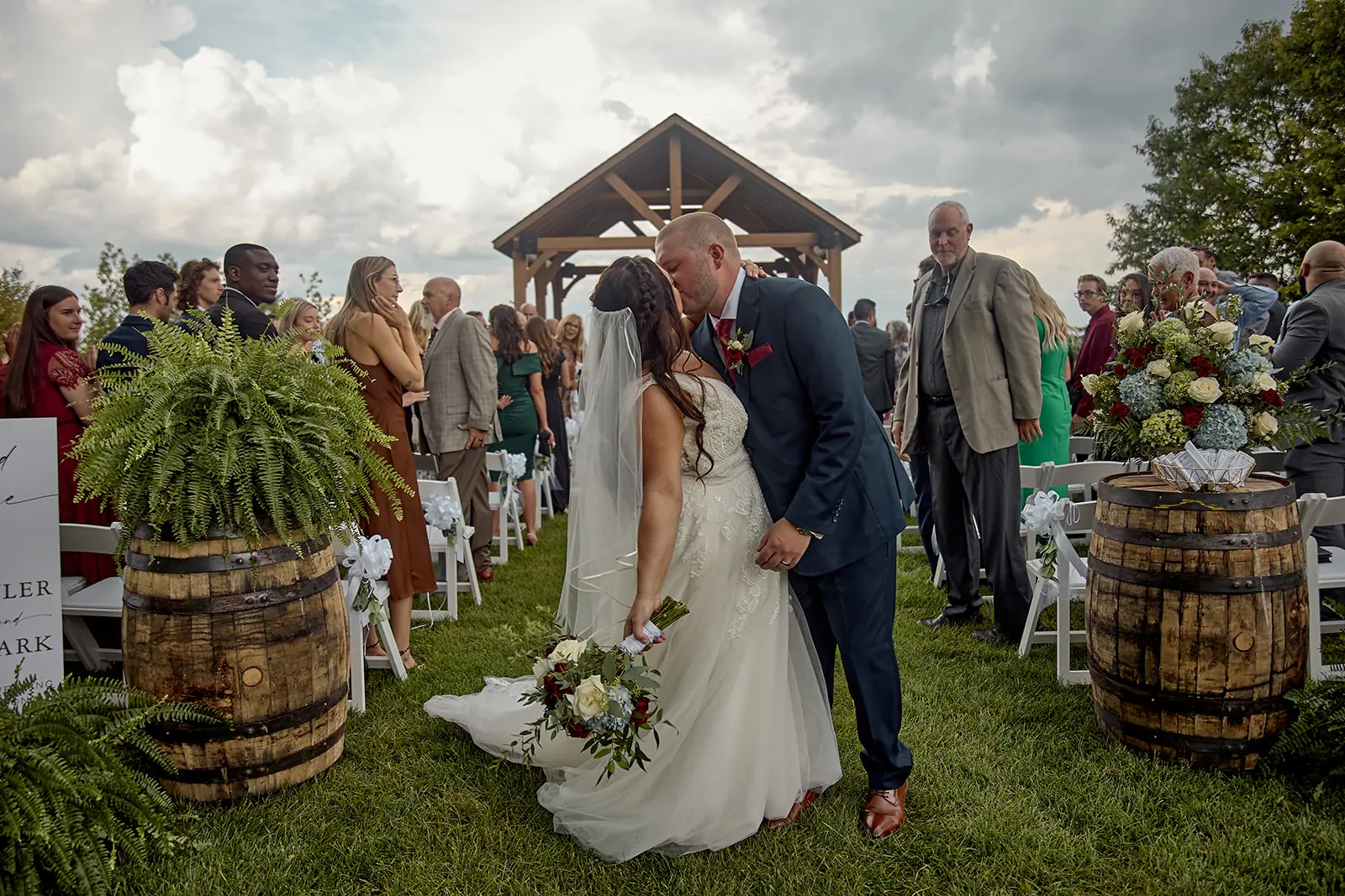 Couple kissing guests applaud pavilion — Taylor & Mark's wedding at The Manor at Fire Tower Hill, Lewiston, MI