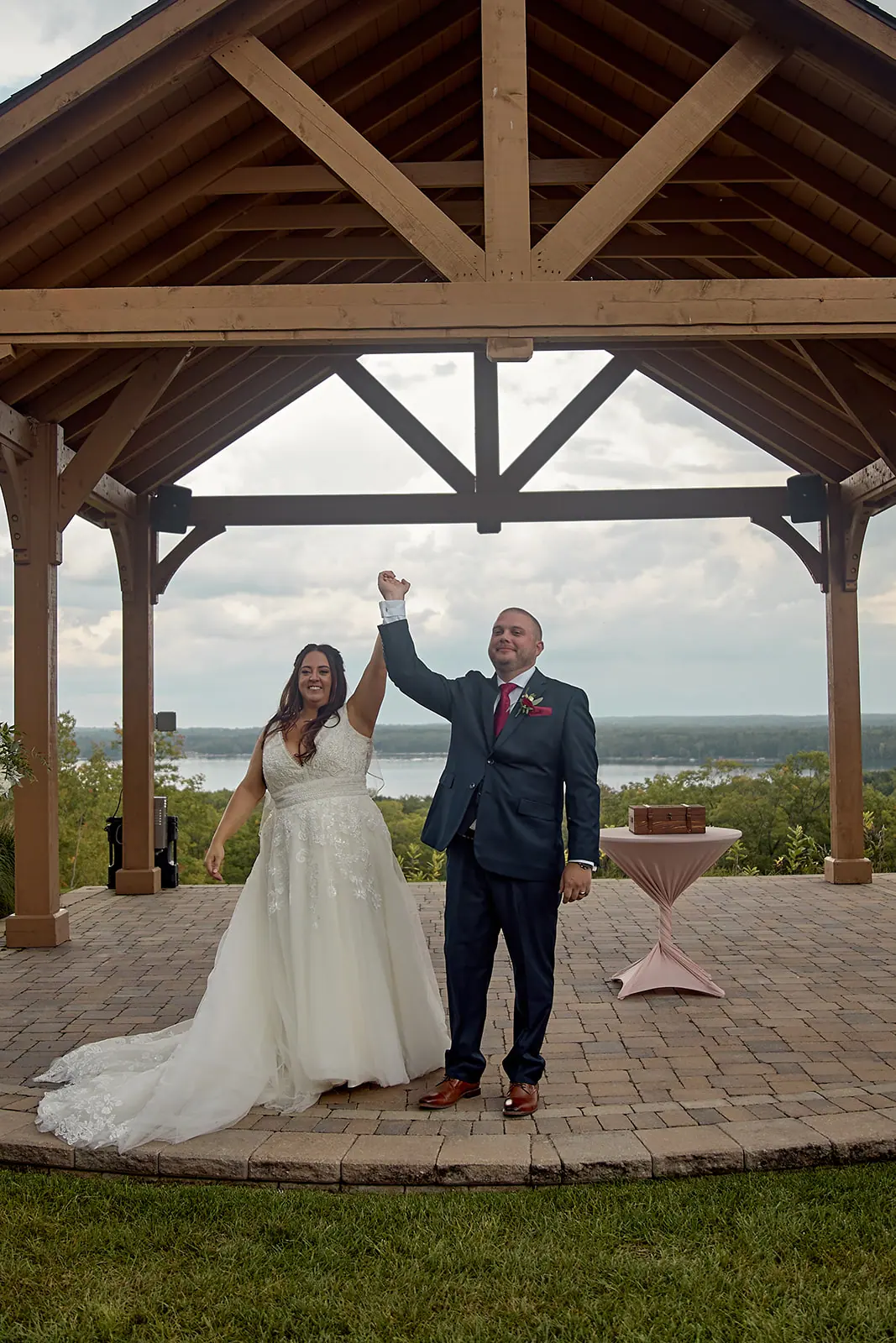 Couple raising hands pavilion pink table — Taylor & Mark's wedding at The Manor at Fire Tower Hill, Lewiston, MI