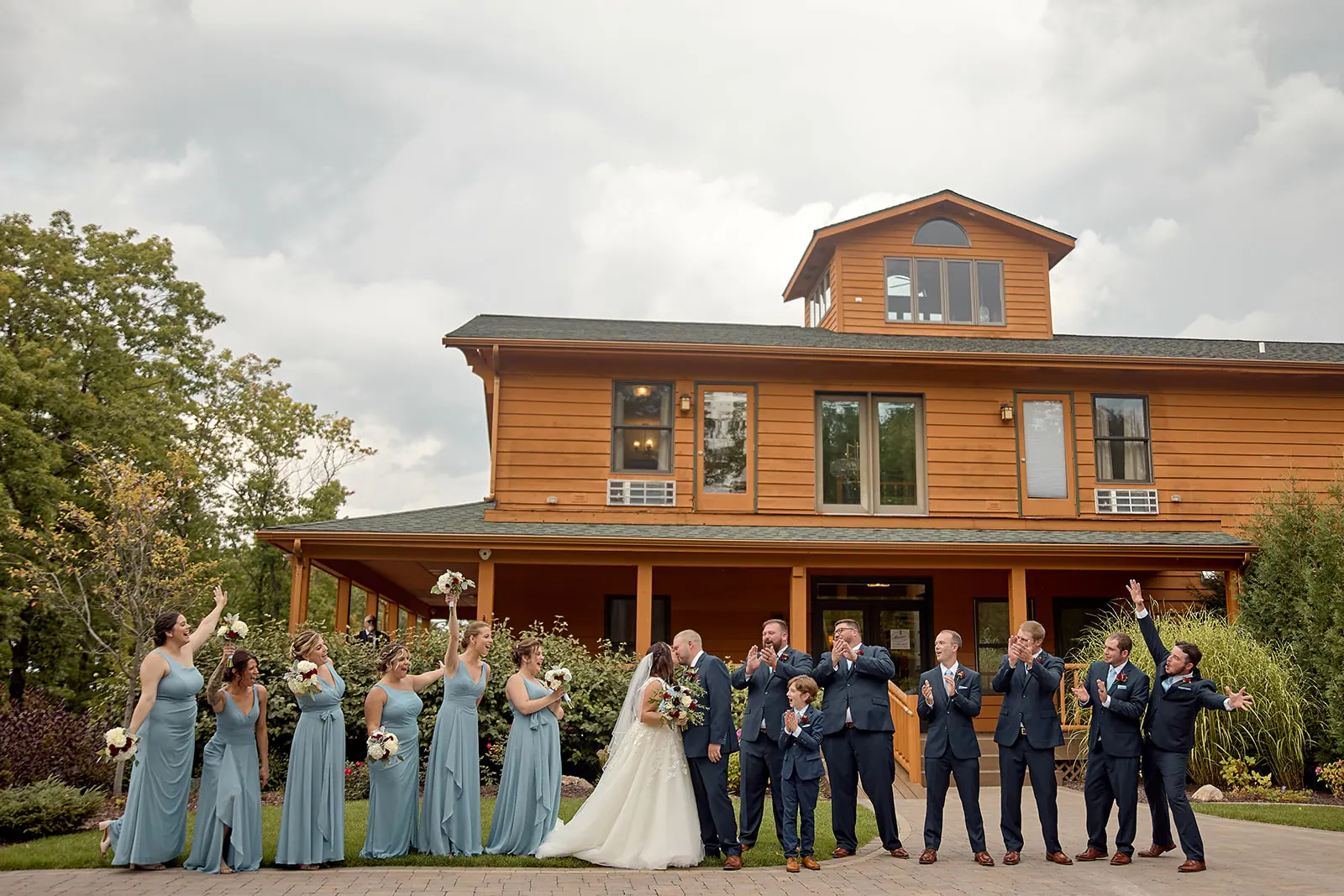 Full wedding party standing front lodge — Taylor & Mark's wedding at The Manor at Fire Tower Hill, Lewiston, MI
