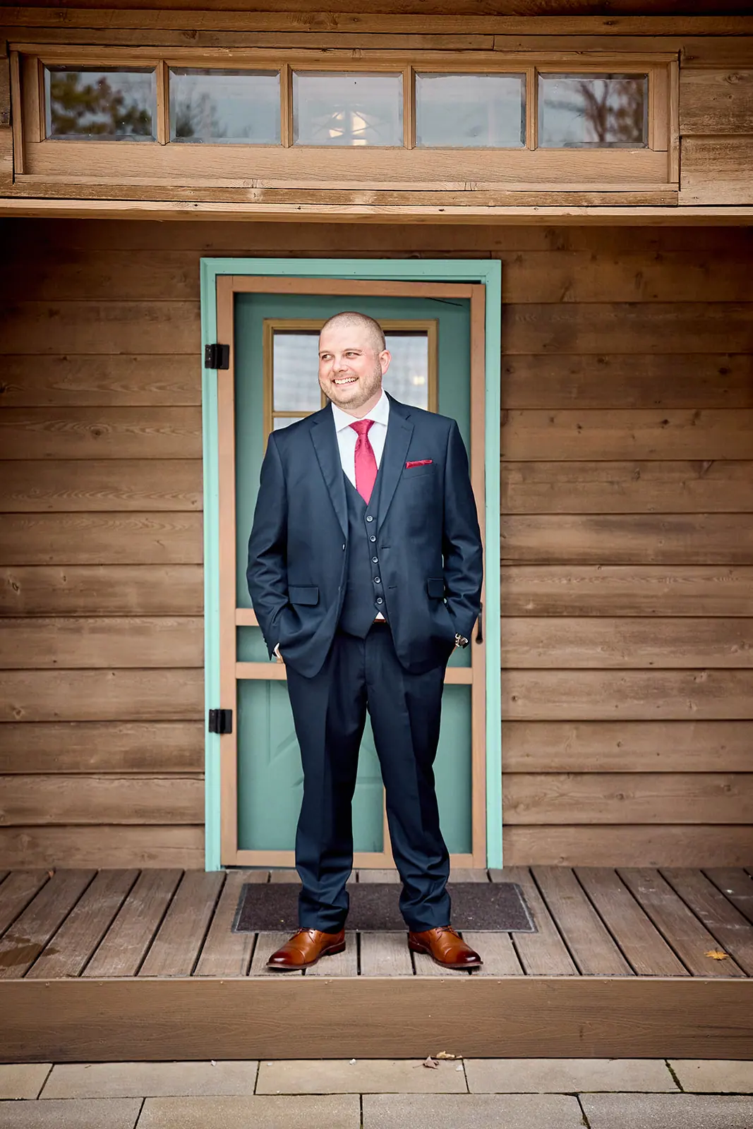 Groom navy suit red tie standing — Taylor & Mark's wedding at The Manor at Fire Tower Hill, Lewiston, MI