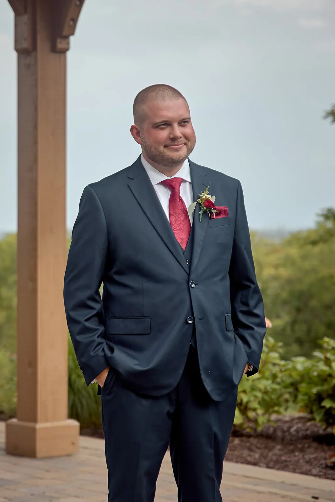 Groom navy suit red tie standing — Taylor & Mark's wedding at The Manor at Fire Tower Hill, Lewiston, MI