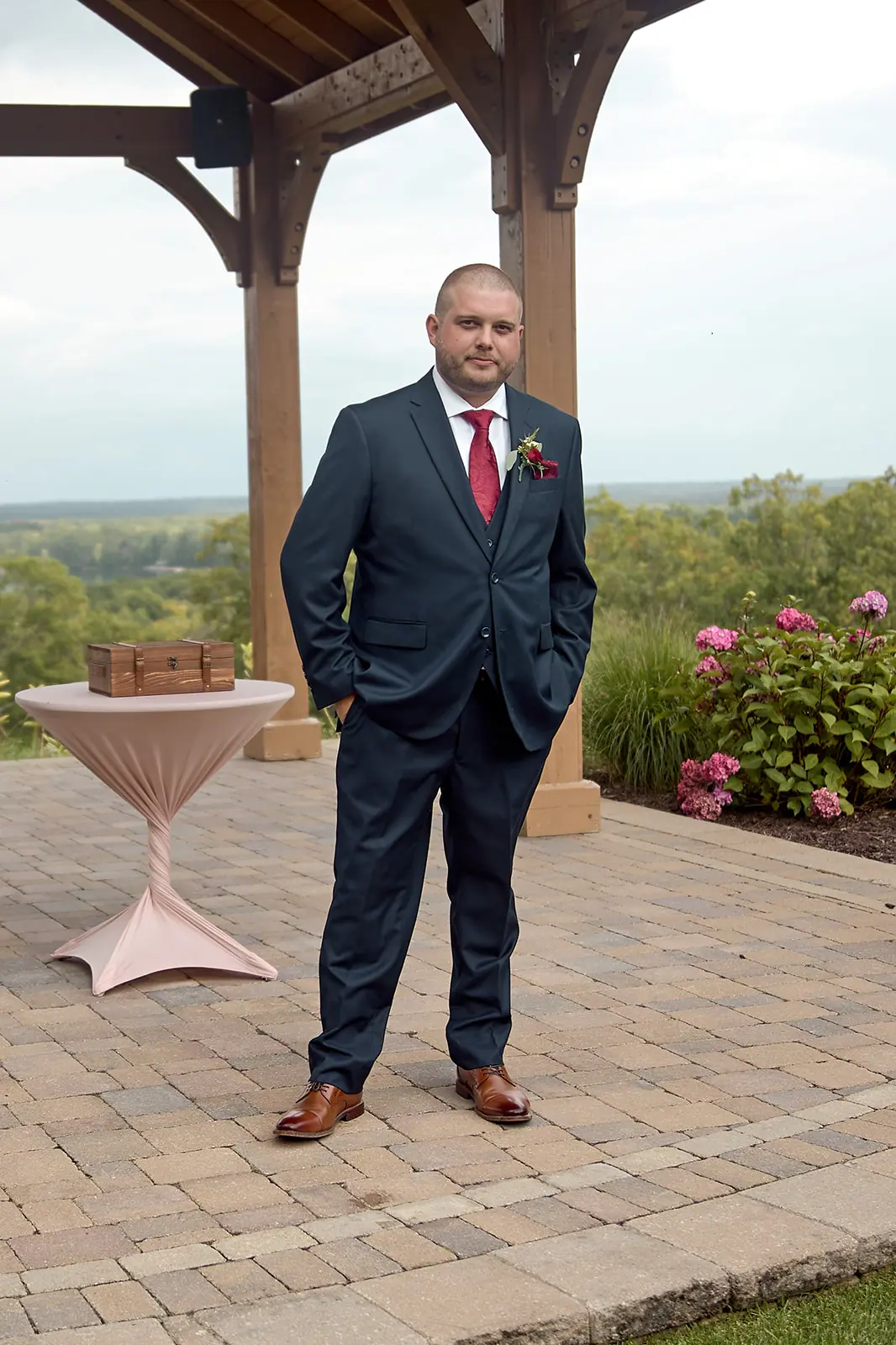 Groom standing wooden pavilion hands pockets — Taylor & Mark's wedding at The Manor at Fire Tower Hill, Lewiston, MI