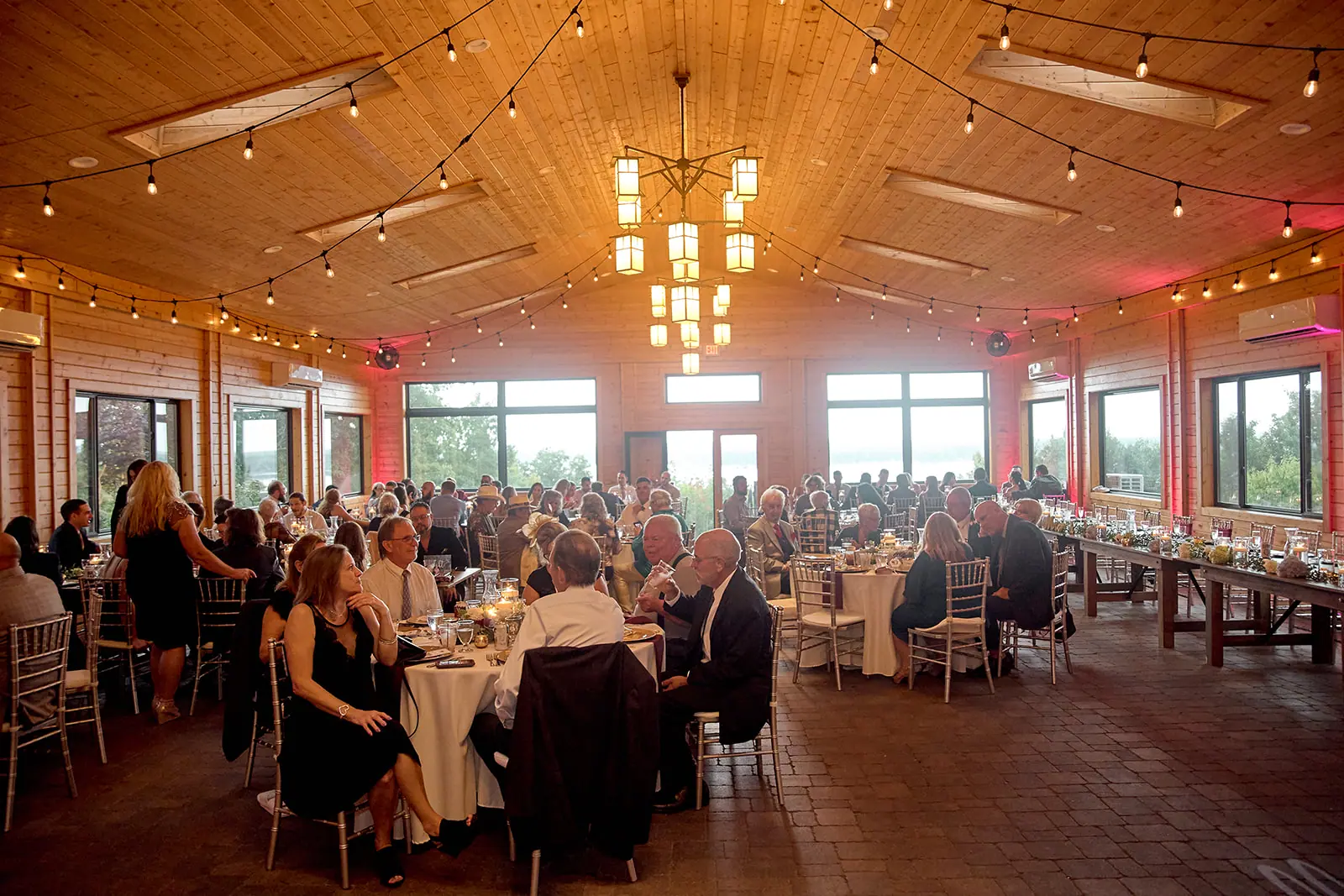 Wide reception hall string lights seated — Taylor & Mark's wedding at The Manor at Fire Tower Hill, Lewiston, MI