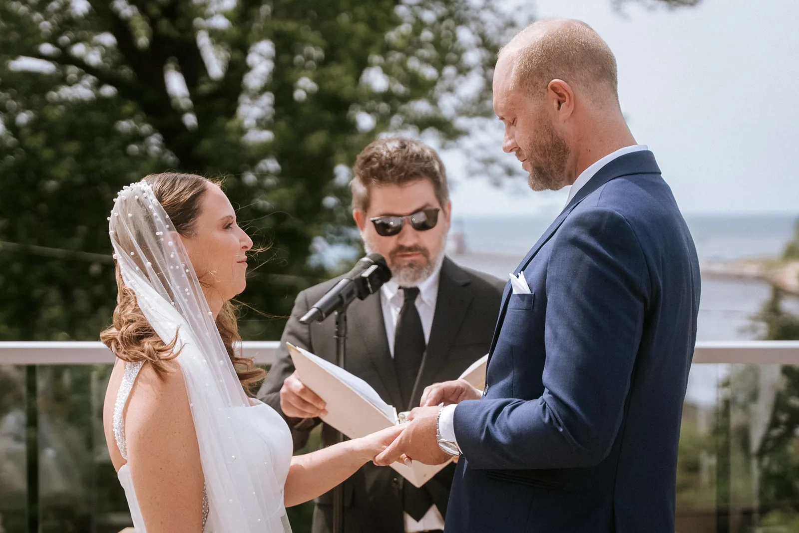 Bride and groom exchanging vows with a lake view behind them
